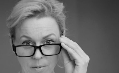 Gözlüklü kadın gri arka planda sergileniyor