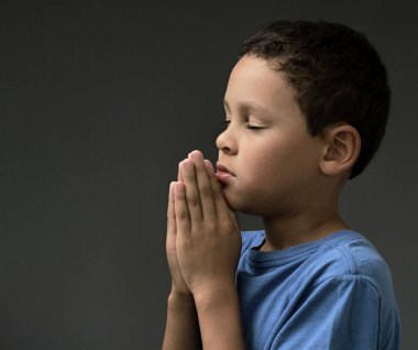 Tanrı 'ya dua eden bir çocuk elleri kapalı, gözleri kapalı ve insanların resimlerini stokluyor.