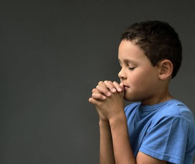 Tanrı 'ya dua eden bir çocuk elleri kapalı, gözleri kapalı ve insanların resimlerini stokluyor.