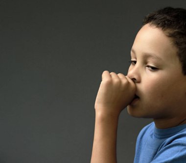 Gri arka planda parmak emen küçük çocuk, insanların resimlerini stokluyor.