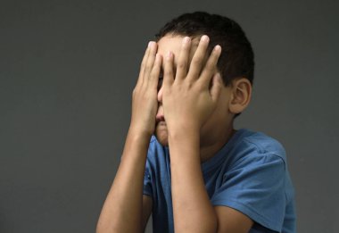 Çocuk Tanrı 'ya dua ediyor, elleri kapalı, gözleri kapalı, gri arka plan fotoğrafında.