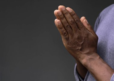 Adam Tanrı 'ya ellerinin birliğiyle dua ediyor Karayipli adam gri siyah arka planda dua ediyor insanların resimli çorap fotoğraflarıyla.