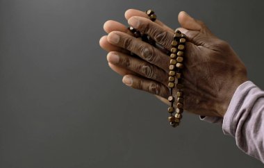 Adam Tanrı 'ya ellerinin birliğiyle dua ediyor Karayipli adam gri siyah arka planda dua ediyor insanların resimli çorap fotoğraflarıyla.