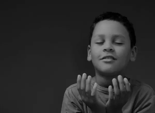 boy praying to God with hands held together with closed eyes with people stock image stock photo
