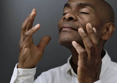 Siyah adam gri siyah arka planda Tanrı 'ya dua ediyor ve insanların resimlerini stokluyor.