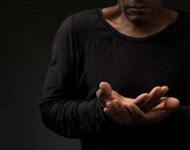 Adam Tanrı 'ya ellerinin birliğiyle dua ediyor. Karayipli adam insanların resimlerini stoklayarak dua ediyor.