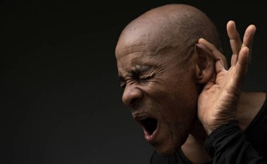 Gri arka planda sağırlık ve işitme kaybı yaşayan bir adam.