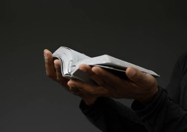 Adam siyah arka planda İncil 'le Tanrı' ya dua ediyor ve insanların resimlerini stokluyor.