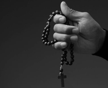 Siyahi adam Tanrı 'ya gri siyah arka planda el ele dua ederken insanların resimlerini stokluyor.