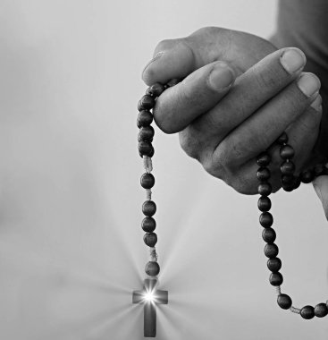 Siyahi adam Tanrı 'ya gri siyah arka planda el ele dua ederken insanların resimlerini stokluyor.