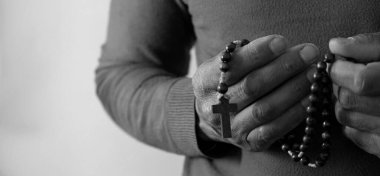 Siyahi adam Tanrı 'ya gri siyah arka planda el ele dua ederken insanların resimlerini stokluyor.