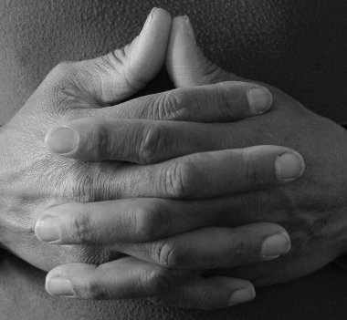 Siyahi adam Tanrı 'ya gri siyah arka planda el ele dua ederken insanların resimlerini stokluyor.