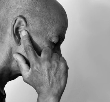 Sağır bir adam, gri siyah arka planda işitme kaybı yaşıyor.