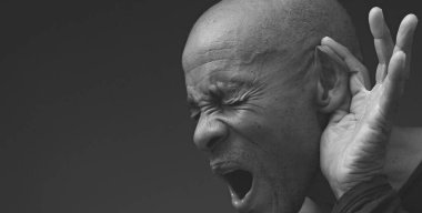 Sağırlık ve işitme kaybından muzdarip bir adam gri siyah arka planda.