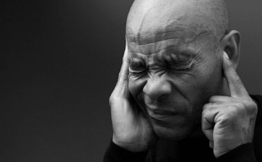 Sağırlık ve işitme kaybından muzdarip bir adam gri siyah arka planda.