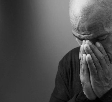 Adam siyah gri arkaplanda Tanrı 'ya dua ediyor ve insanların resimlerini stokluyor.