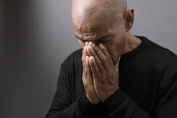 Adam siyah gri arkaplanda Tanrı 'ya dua ediyor ve insanların resimlerini stokluyor.