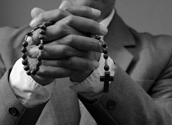 praying to God with hands together on black grey background with people stock image stock photo