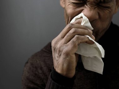 Grip ve nezle olduktan sonra burnu silmek. Gri siyah arka planda, insanların resimli fotoğrafları var.