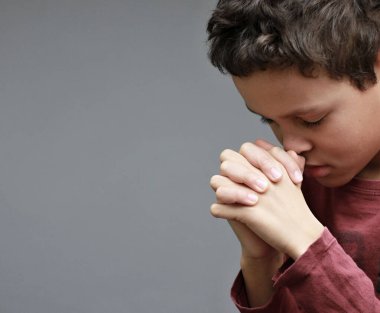 Çocuk tek başına tanrıya dua ediyor. İnsanların resimlerini saklıyor.