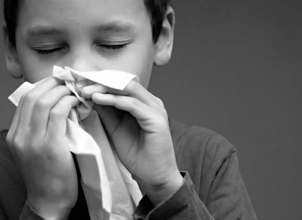 Boy blowing nose after catching a cold