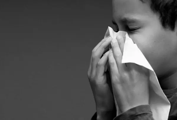Boy blowing nose after catching a cold