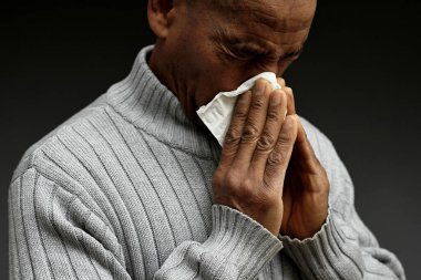 Grip ve nezle olduktan sonra burnu silmek. Gri siyah arka planda, insanların resimli fotoğrafları var.