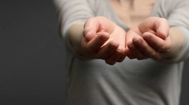 Karanlık arka planda bir şey gösteren kadın, yakın plan.