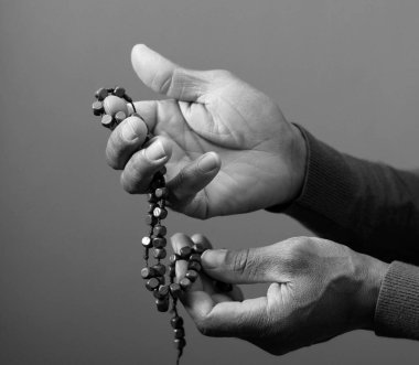 Karanlık arka planda dua eden kişinin elleri, yakın görünüm