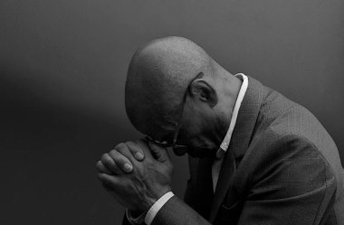 Siyah adam siyah gri arkaplanlı tanrıya dua ediyor.