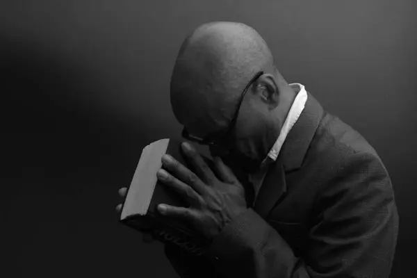 black man praying to god with black grey background