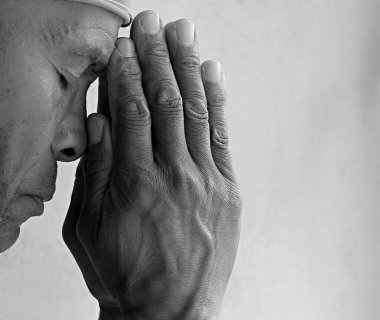 Adam gri siyah arka planda Tanrı 'ya dua ediyor.