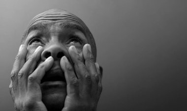 Adam gri siyah arka planda Tanrı 'ya dua ediyor.