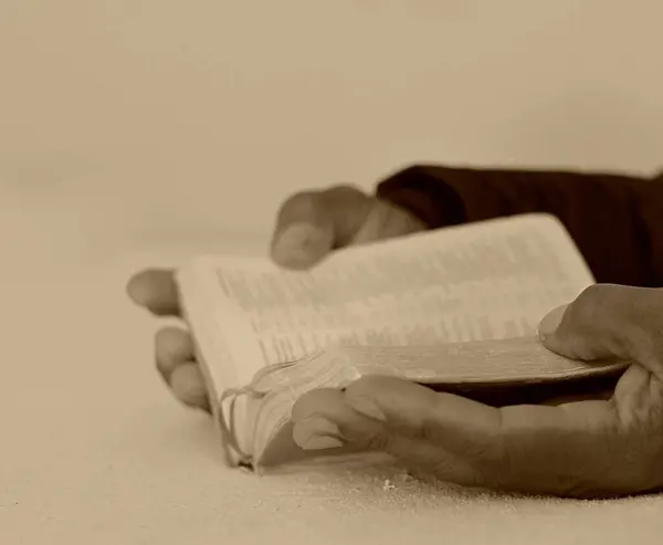 black man people praying to God with hands together on bible