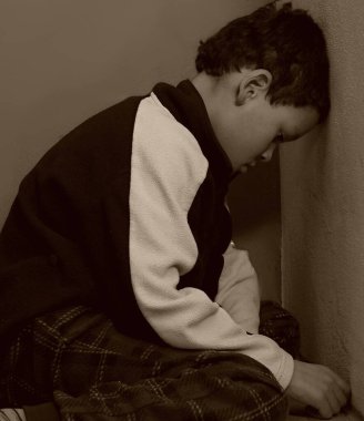 Yoksulluk içinde yerde dua eden çocuk, stüdyo portresi. 