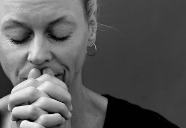 Gri siyah arka planda elleri bağlı dua eden kadın. 