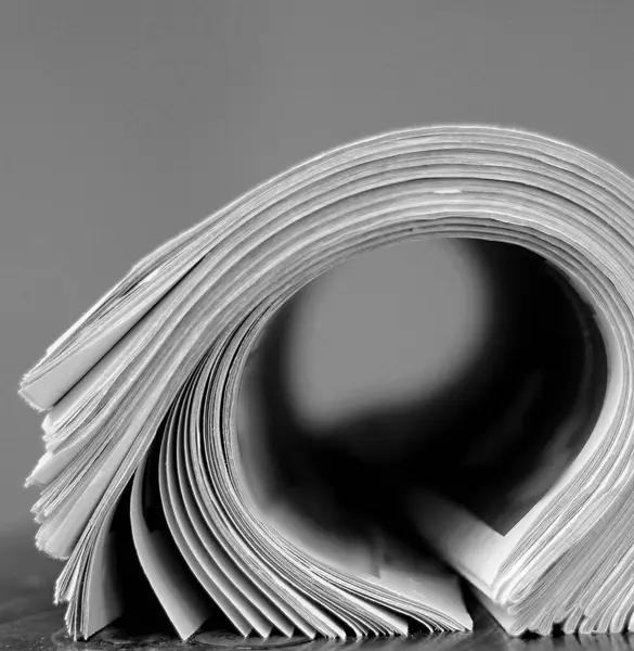 Newspapers piled up on table in office with white background