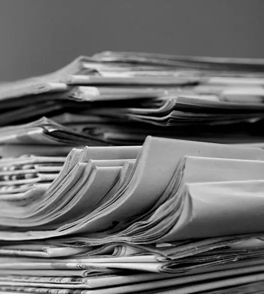 Newspapers piled up on table in office with white background
