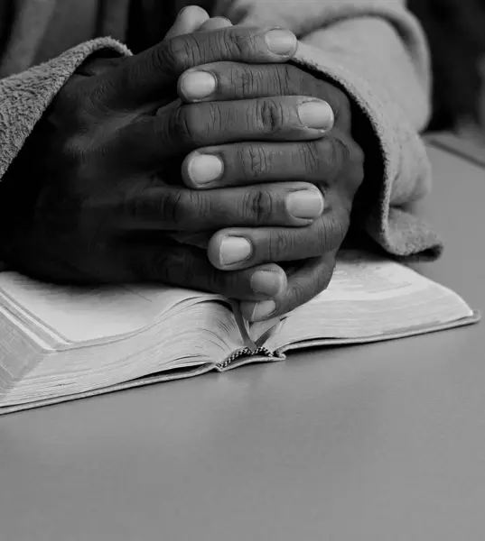 Black man praying god with bible in hands. Caribbean man praying on black background, cropped section
