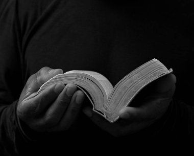 Elinde İncil 'le Tanrı' ya dua eden siyahi bir adam. Karayipli adam siyah arka planda dua ediyor, kırpılmış bölüm