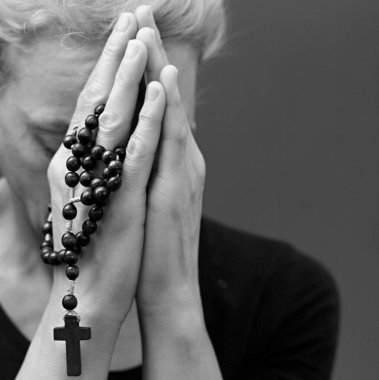 Gri siyah arka planda elleri bağlı dua eden kadın. 