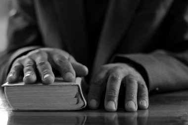 Adam ahşap masada otururken İncil 'le Tanrı' ya dua ediyor. 