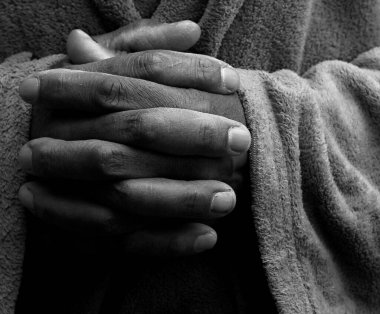 Adam Tanrı 'ya dua ediyor, elleri koyu arkaplanda.