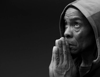 Adam Tanrı 'ya dua ediyor, elleri koyu arkaplanda.