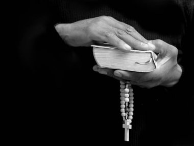 Tanrı 'ya dua eden bir adam. Siyah arka planda haç ile birlikte.