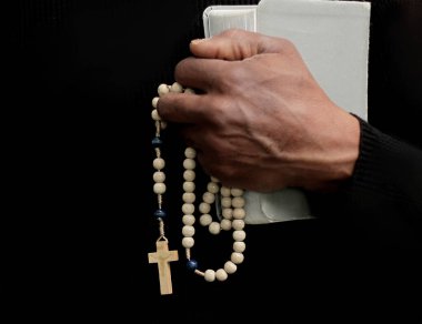 Tanrı 'ya dua eden bir adam. Siyah arka planda haç ile birlikte.