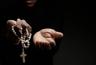Tanrı 'ya dua eden bir adam. Siyah arka planda haç ile birlikte.