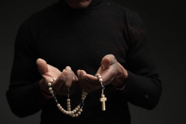 Karanlık arka planda Tanrı 'ya dua eden bir adam. 