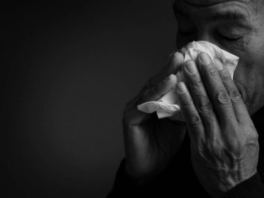 Hasta bir adamın burnunu sildiği siyah beyaz bir görüntü. 