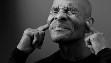 Kulaklarını kapatan Afrikalı Amerikalı bir adamın portresi. 